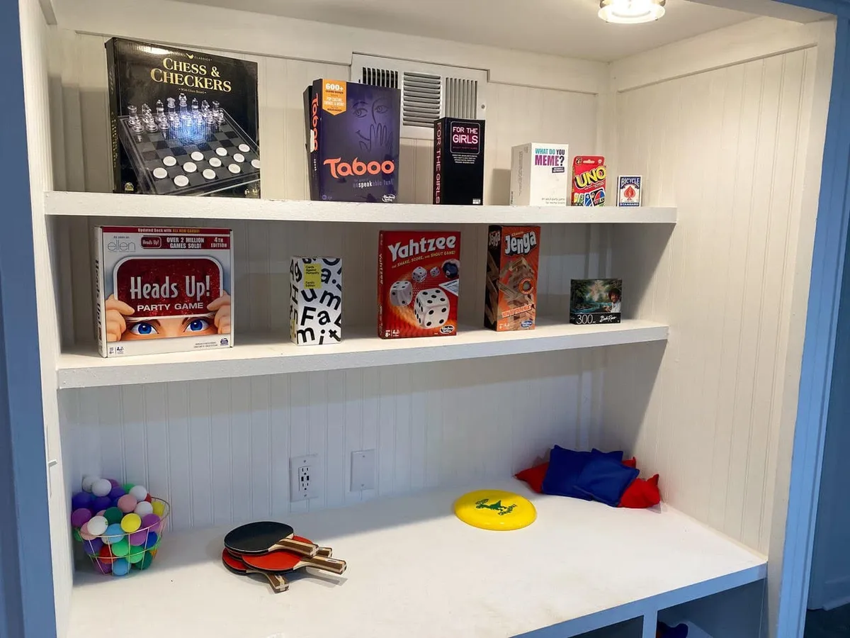 A colorful interior scene centered on a table with a variety of board and card games set up, surrounded by bright, playful decor. The area is ready for friendly competition and group interaction.