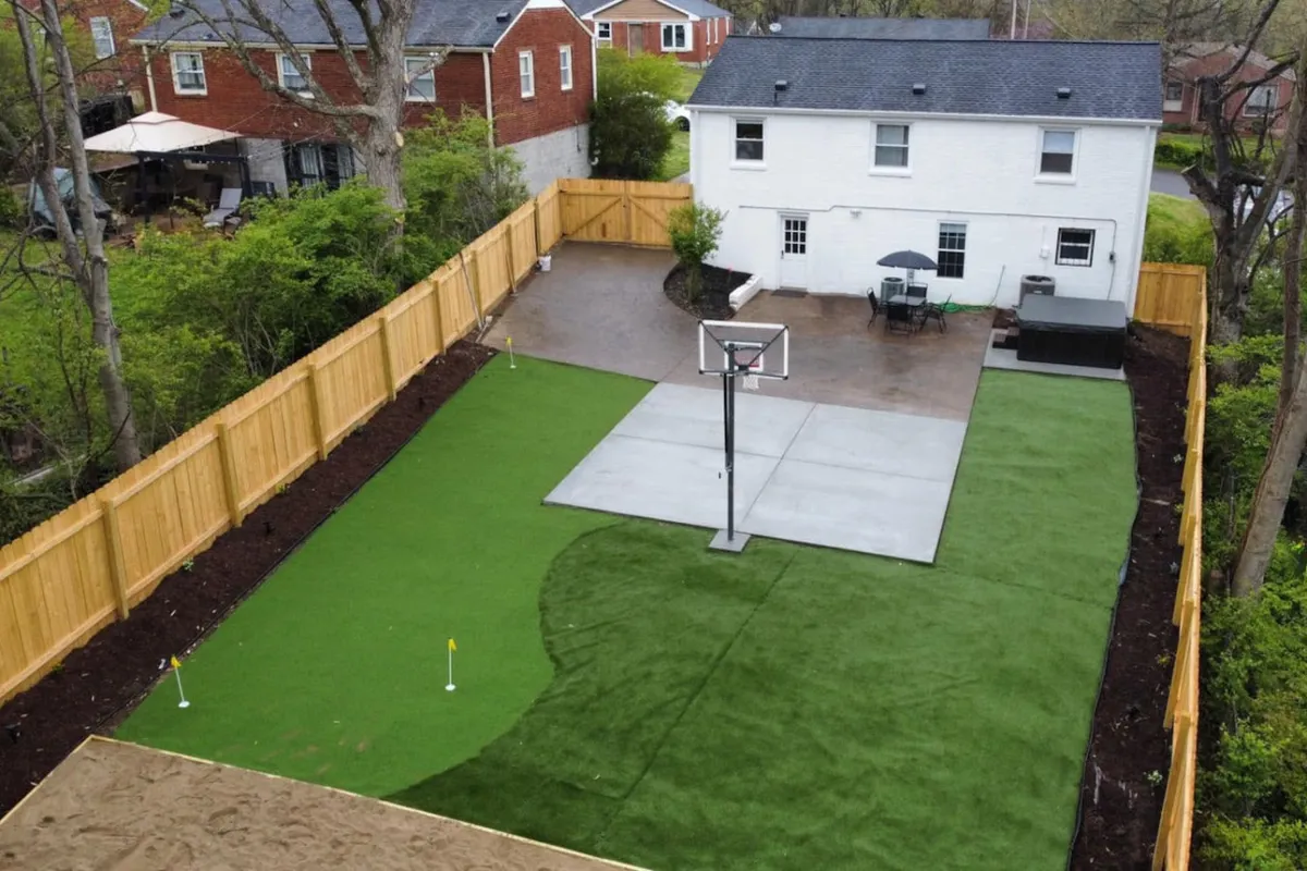 The image showcases the home's inviting backyard with a basketball hoop, lush green lawn, and a spacious patio area outfitted with cozy seating—perfect for barbecues and relaxed gatherings. It exudes a playful, welcoming vibe ideal for groups looking to enjoy both activity and relaxation.